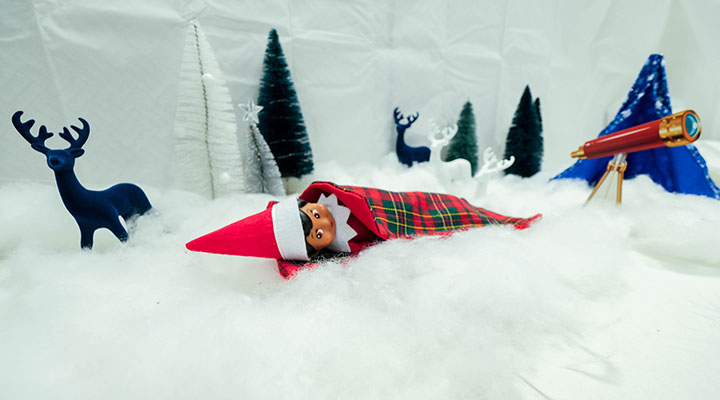 elf on a shelf in a sleeping bag while camping outdoors